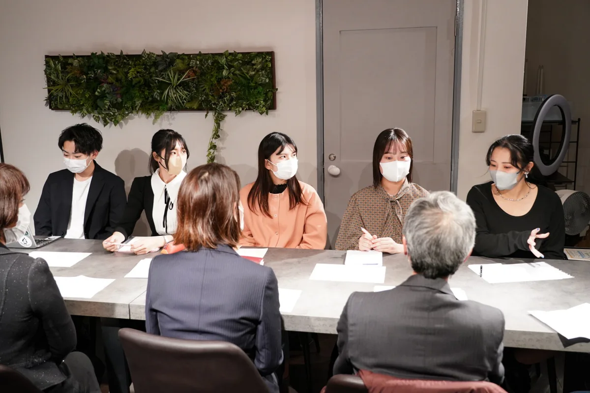 テーブルを囲み企業担当者と話す大学生